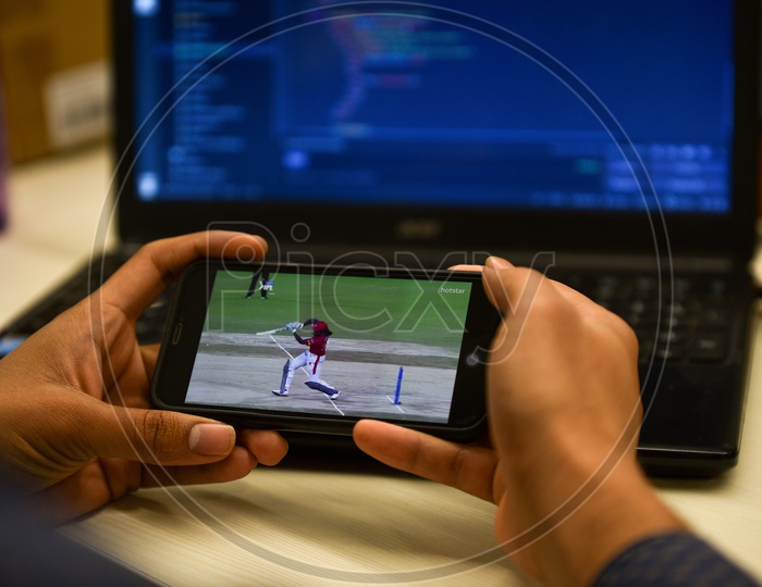 Indian user watching IPL match on Hotstar app in Mobile while working in Office