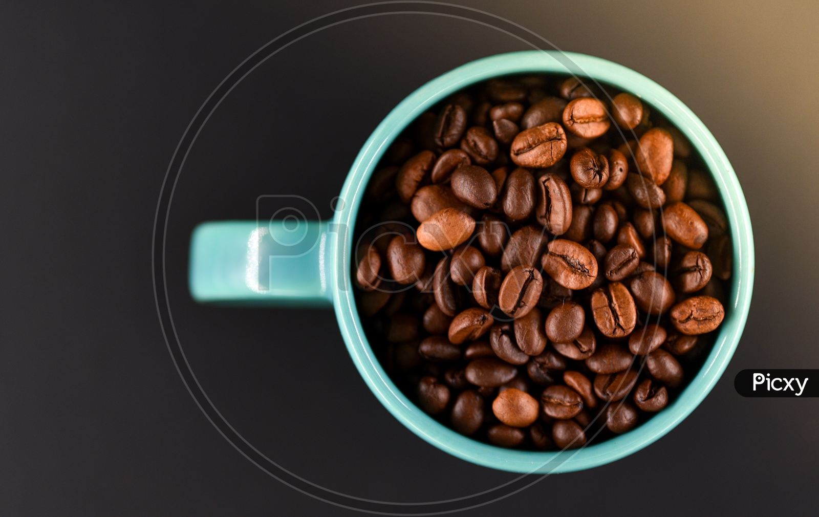 Coffee beans in a blue coffee mug on a black background