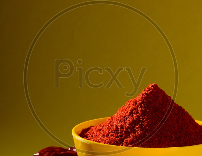 chili powder in yellow bowl on yellow background. Red chilly pepper