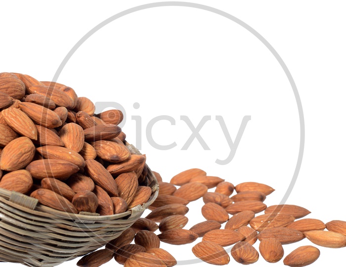Almonds Or Badam Nuts Heap  On a Wooden Weaved Bowl On An Isolated White Background