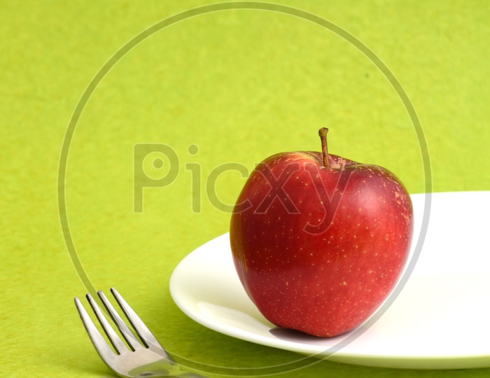 Fresh Red Apple On a White Plate With Knife And Fork on an Isolated Background