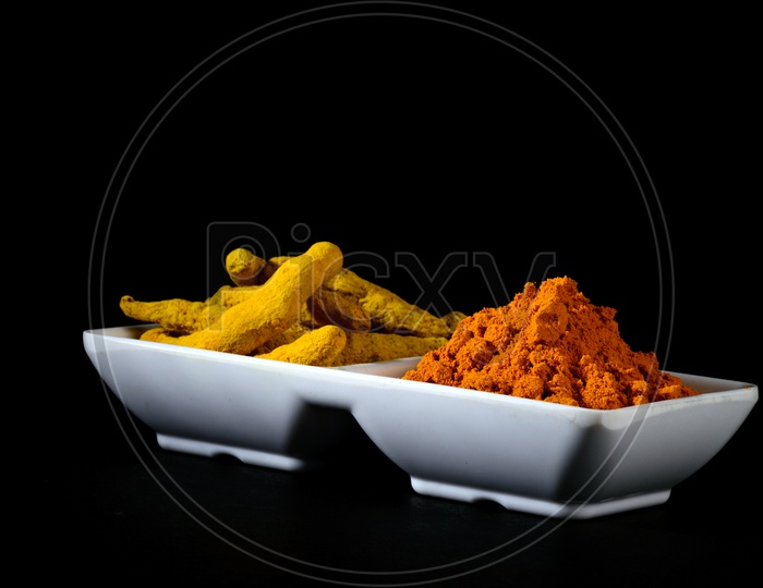 Dry Turmeric powder and roots or barks in white plate