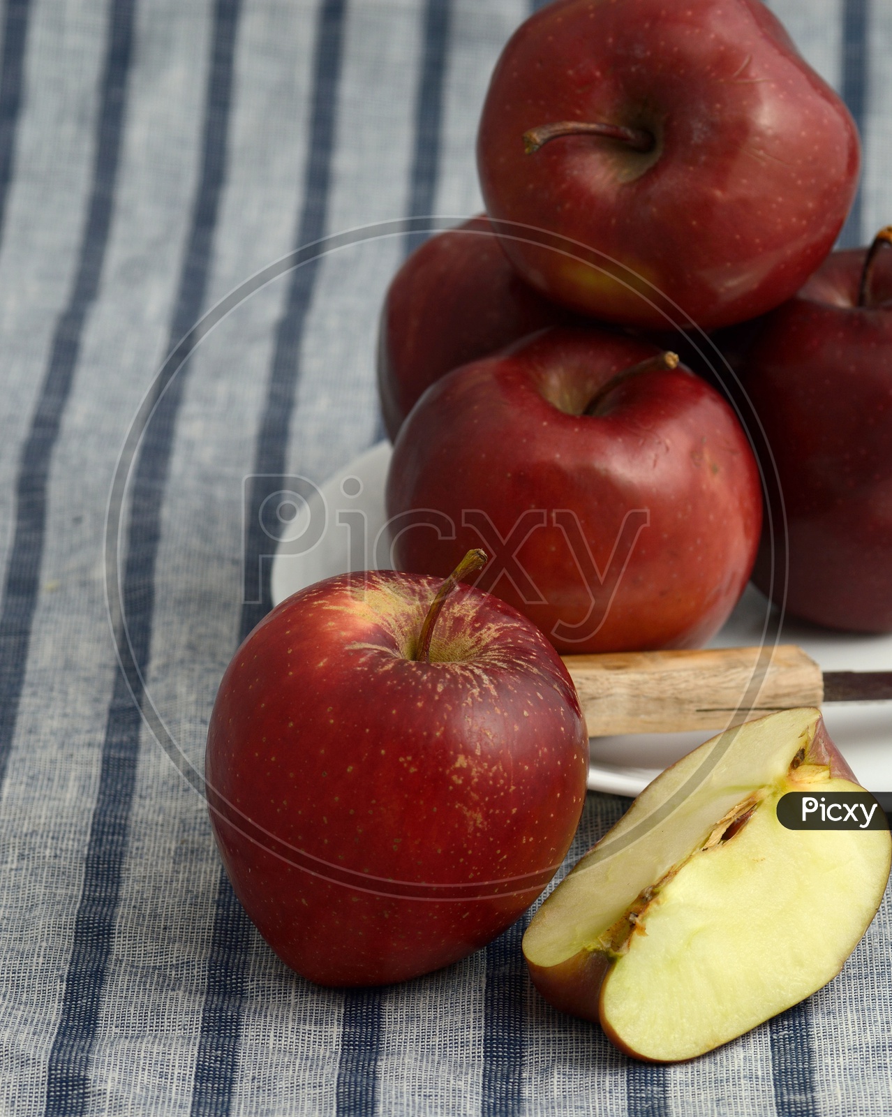 Fresh Red Apples And Slices on a White Plate With Knife  on an Table Cloth Background
