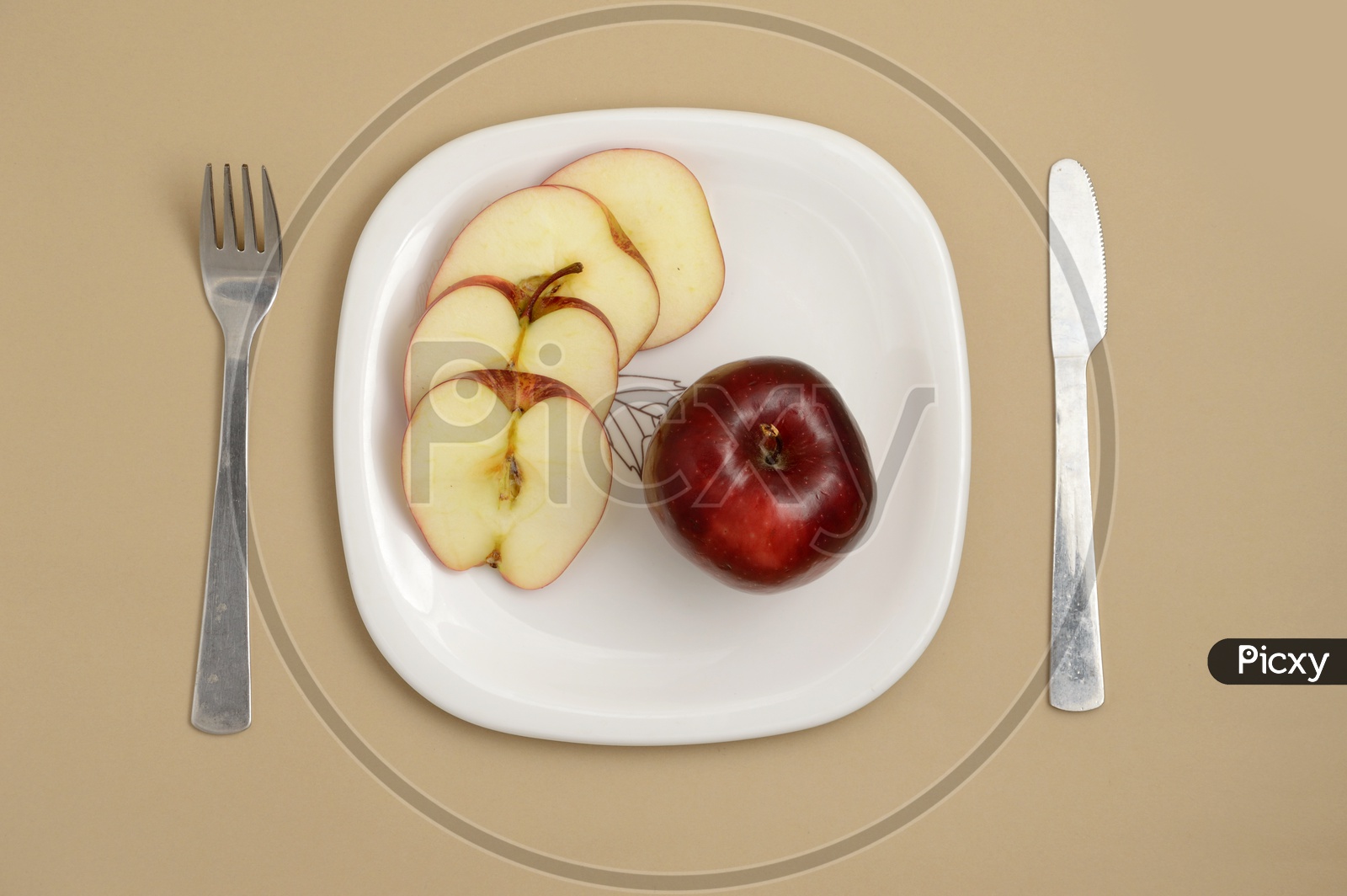 Fresh Red Apple Slices on White Plate With Fork and Knife On an Isolated Background