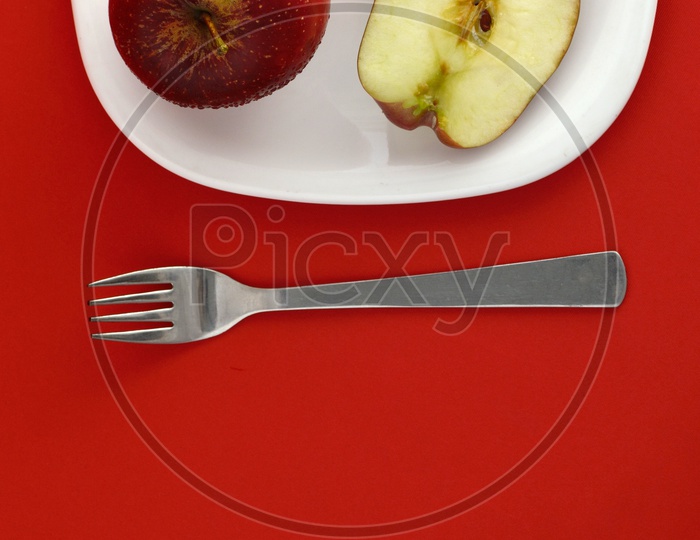 Ripen Red Apple Slices On White Plate With Fork   Over an Isolated Red Background
