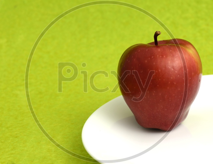 Fresh Red Apple On an  White Plate over an Isolated Green Background