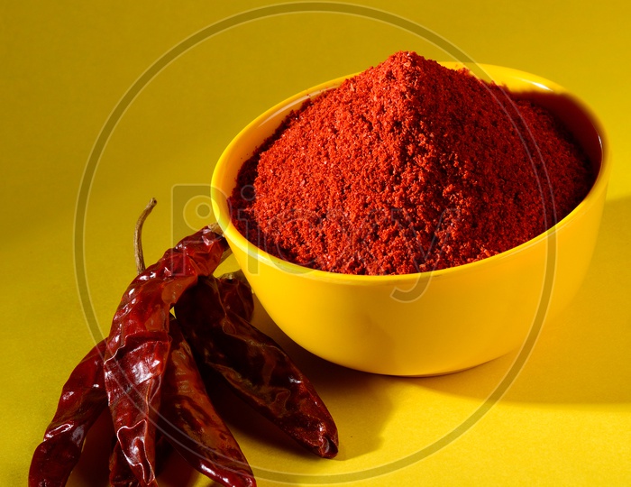 chilly powder in yellow bowl on yellow background. Red chilly pepper