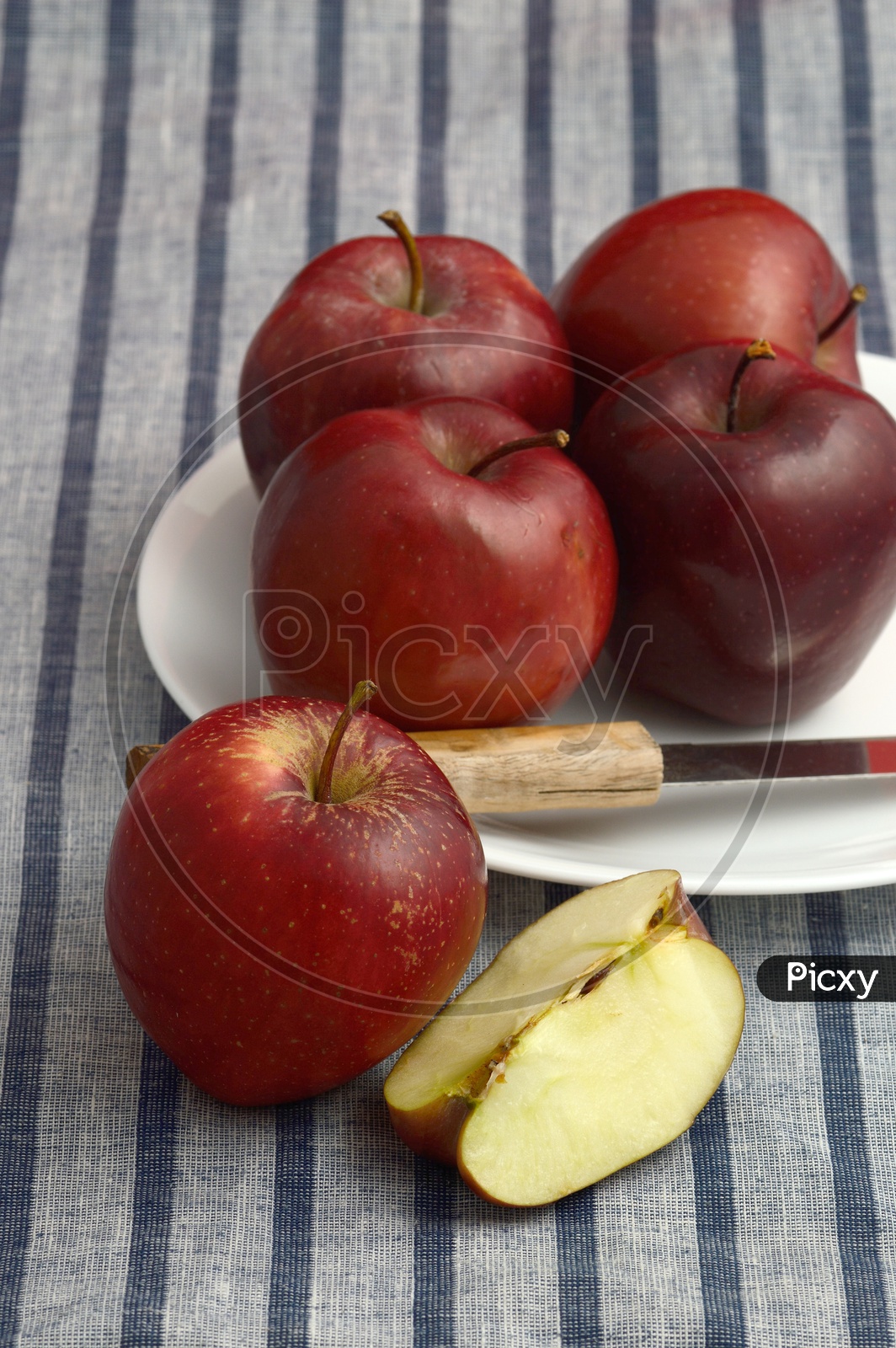 Fresh Red Apples And Slices on a White Plate With Knife  on an Table Cloth Background