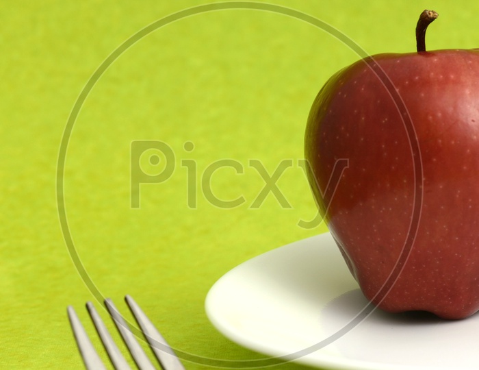 Fresh Red Apple On a White Plate With Knife And Fork on an Isolated Background