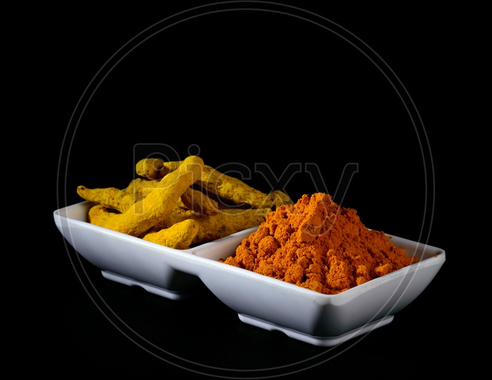 Dry Turmeric powder and roots or barks in white plate