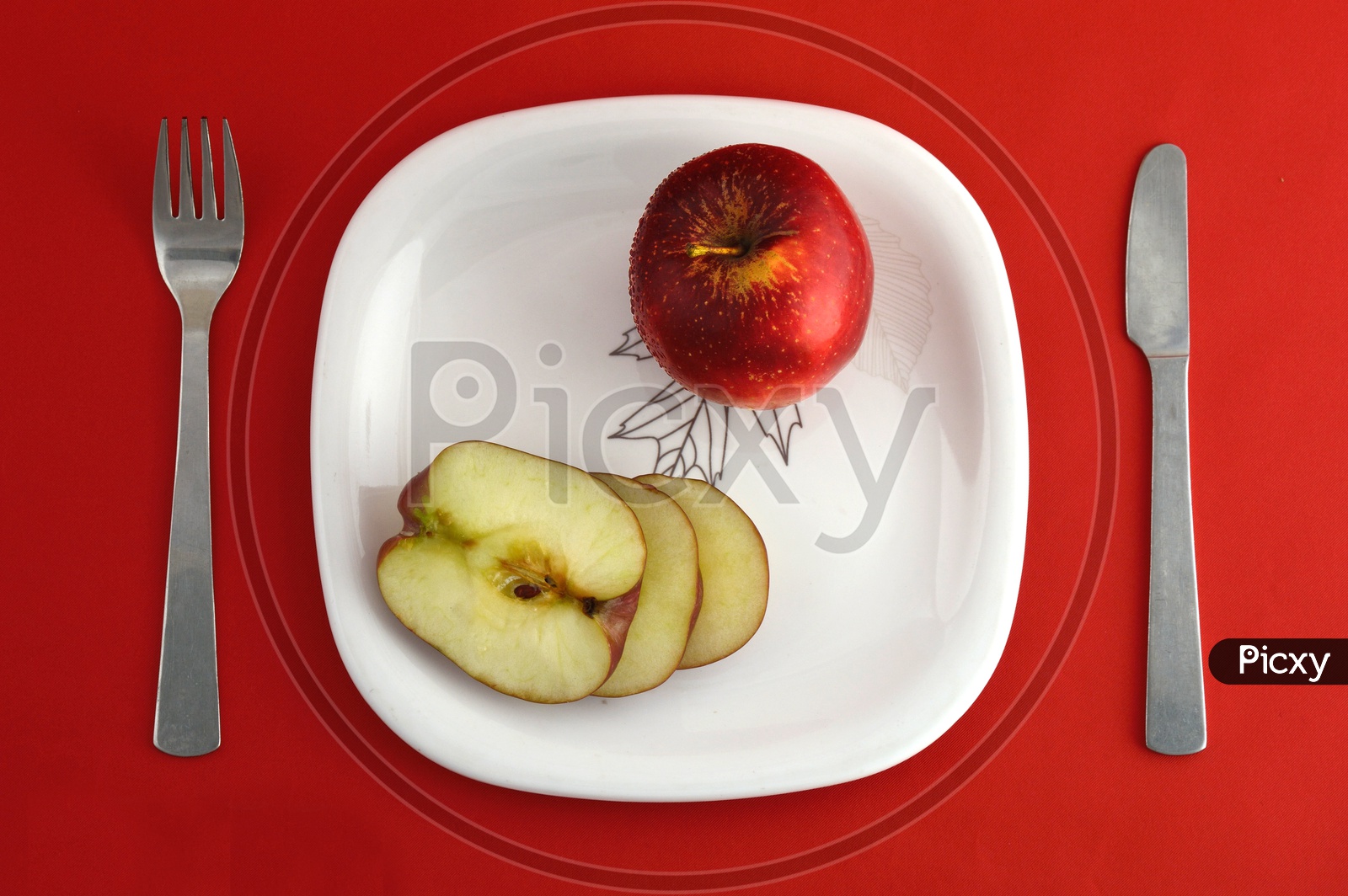 Ripen Red Apple Slices On White Plate   Over an Isolated Red Background