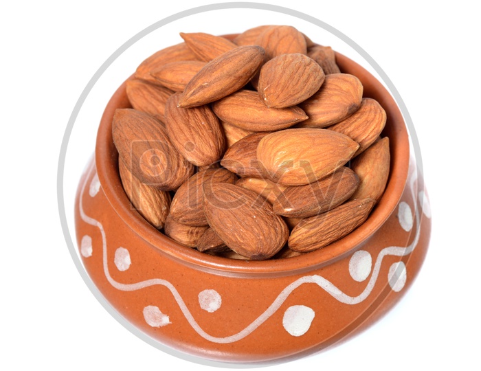 Almonds Or Badam Nuts In a Clay Bowl With a Heap On an Isolated White background