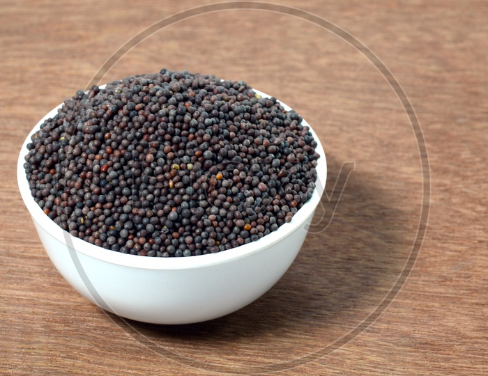 Indian Brown Mustard Seeds in bowl on Wooden table  Background