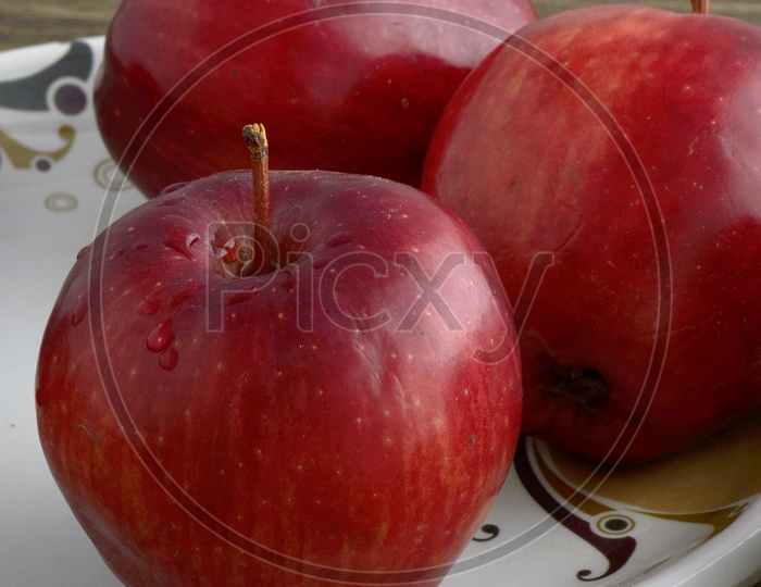 Ripen Red Apples  On a  Plate Over an Isolated Wooden  Background