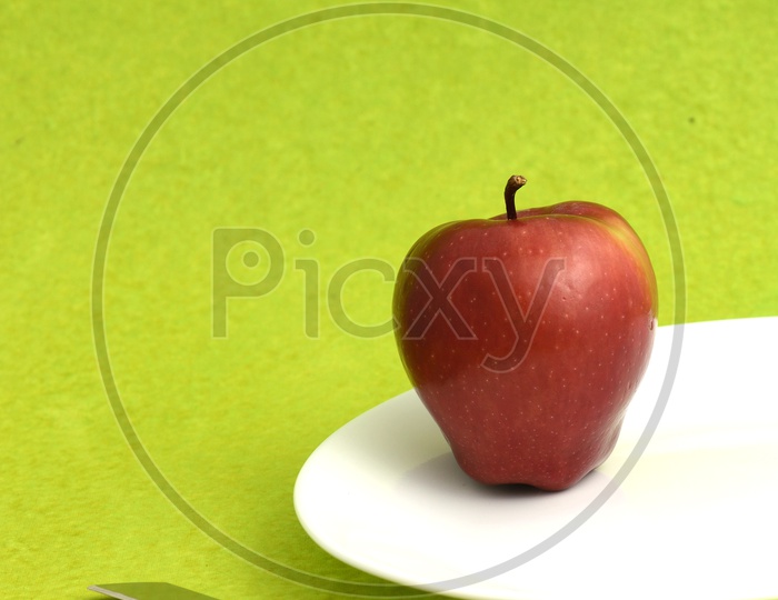 Fresh Red Apple On a White Plate With Knife  on an Isolated Background