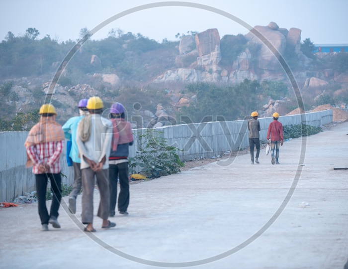 Construction Daily Workers Walking Along a Road Wearing Safety Helmets