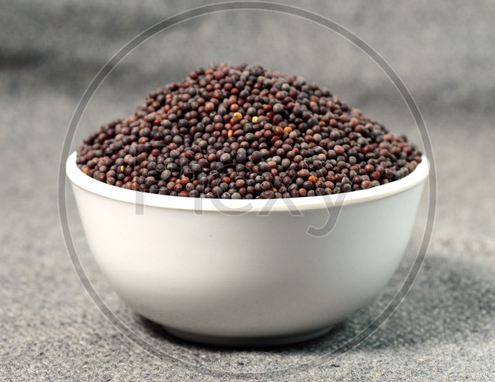 Indian Brown Mustard Seeds in bowl on sackcloth Background