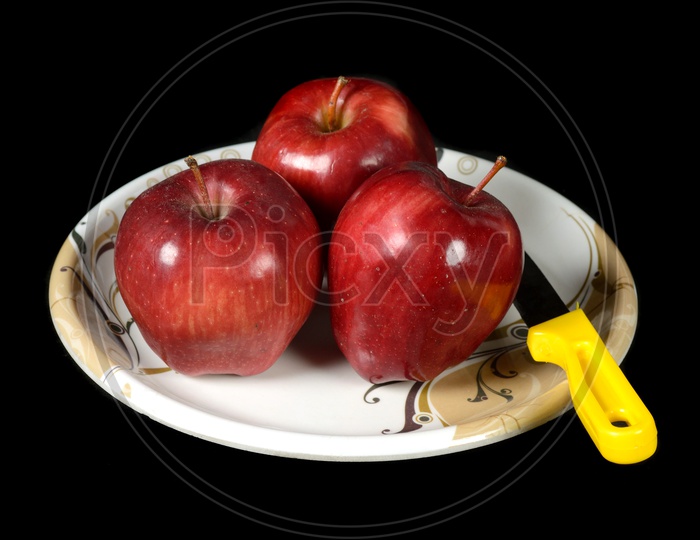 Ripen Red Apples With Knife  On a  Plate Over an Isolated Black Background