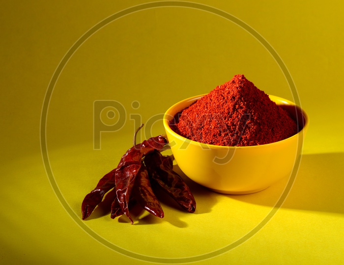 chili powder in yellow bowl on yellow background. Red chilly pepper