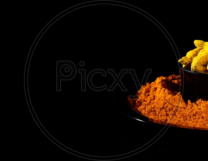 Turmeric powder and roots or barks on black background
