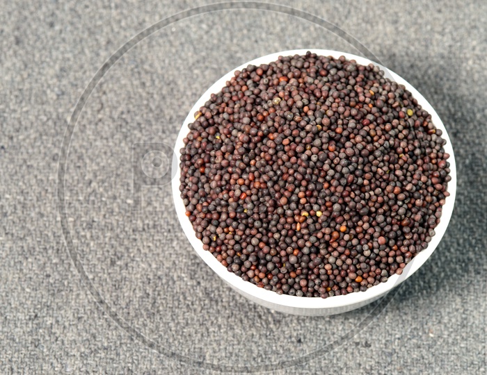 Image of Indian Brown Mustard Seeds in bowl on sackcloth Background