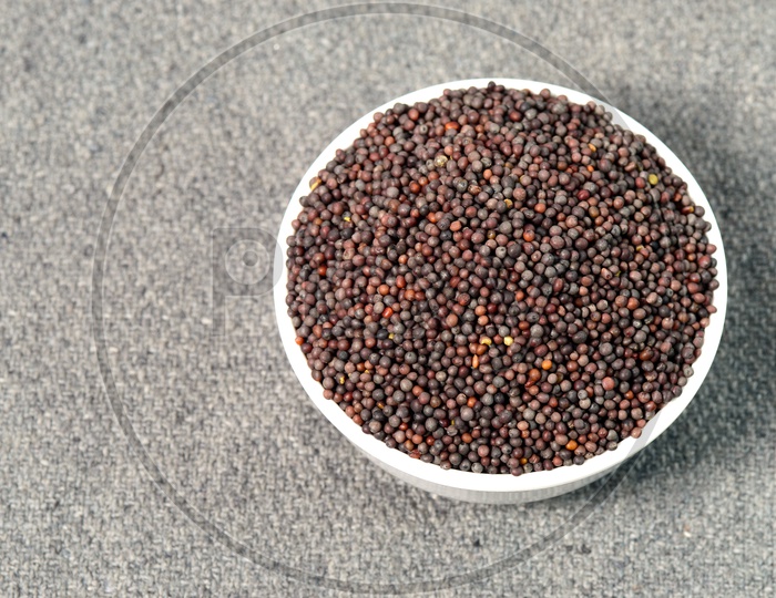 Indian Brown Mustard Seeds in bowl on sackcloth Background