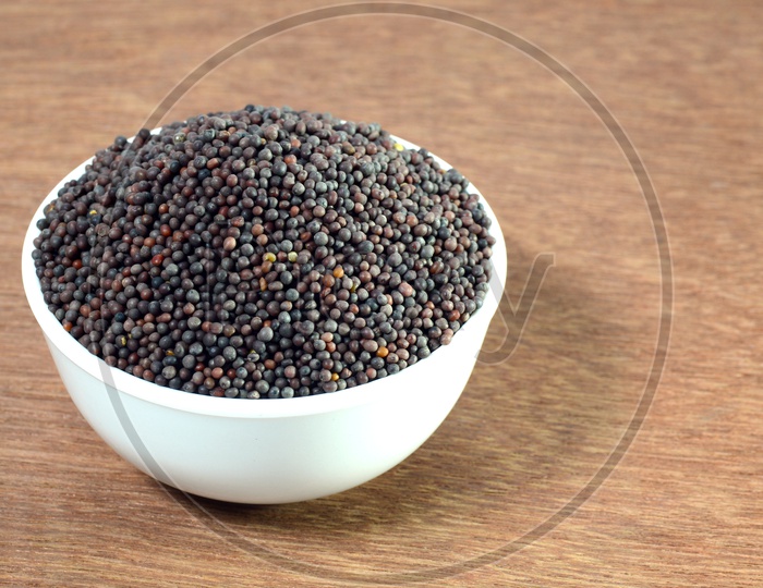 Indian Brown Mustard Seeds in bowl on Wooden table  Background