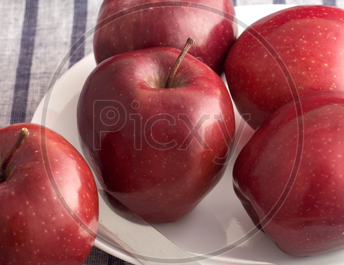 Fresh Red Apples On a White Plate With Knife On an Table Cloth Background