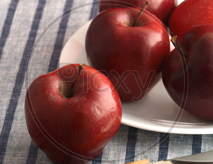 Fresh Red Apples On a White Plate With Knife On an Table Cloth Background