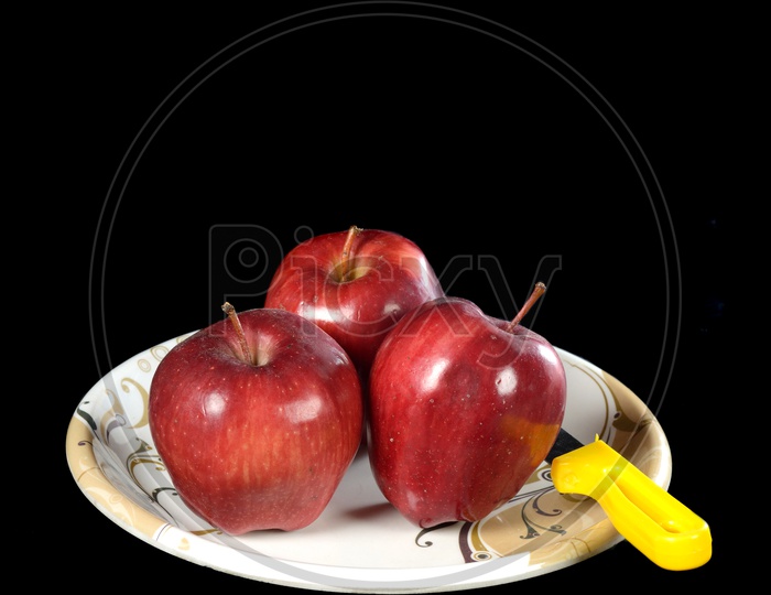 Ripen Red Apples With Knife  On a  Plate Over an Isolated Black Background