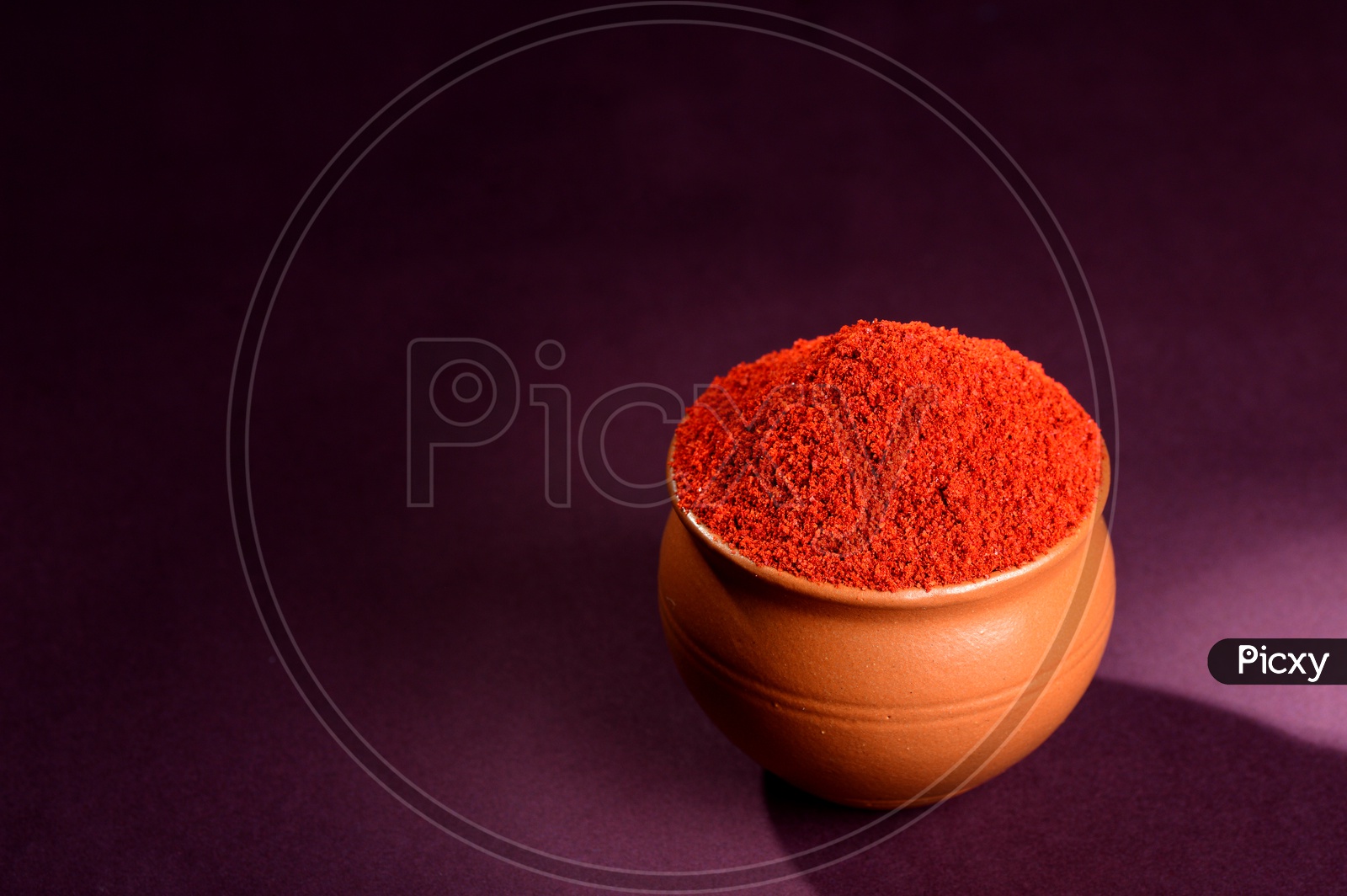 Red Chili Pepper powder in clay pot on dark background