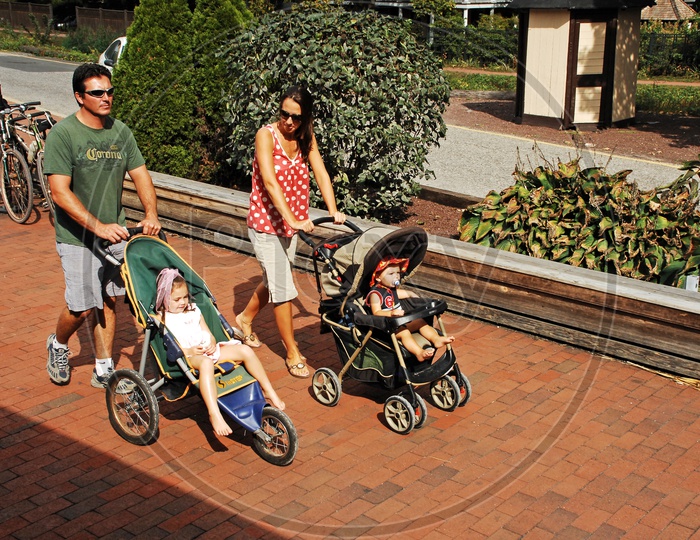 Parents taking their toddlers for a stroll in baby carriage