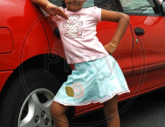 Indian little girl posing alongside the car
