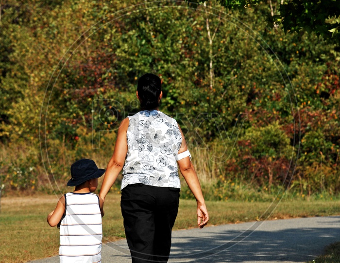 Mother and son walking along the road in the park