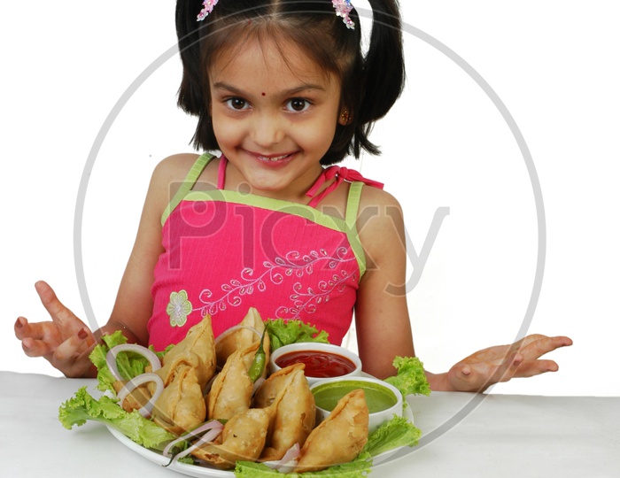 Indian girl with samosas in front of her