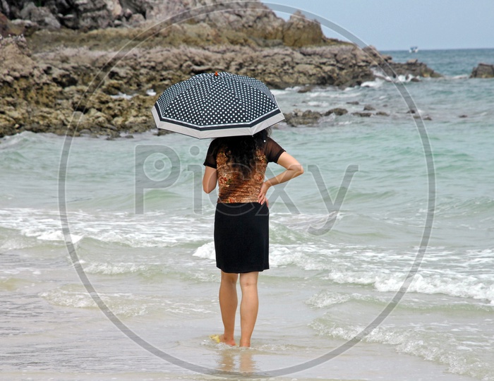 A Young Woman Standing Under Umbrella in a Beach