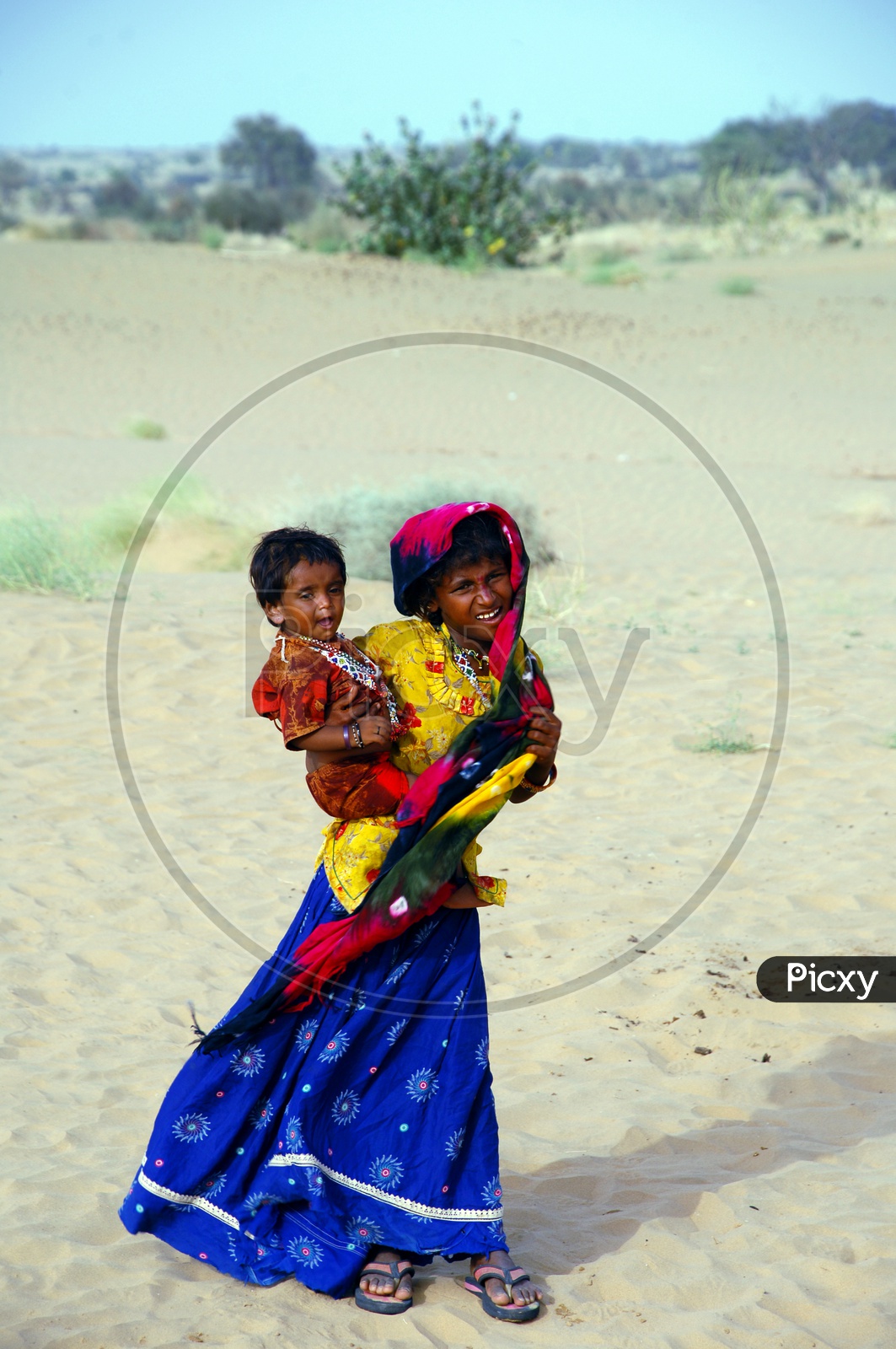 A girl carrying little girl in the desert