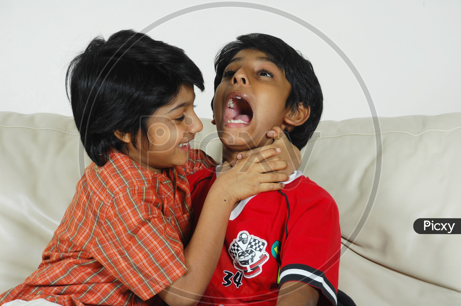 Image of Two boys fighting playfully on the couch-KW953258-Picxy