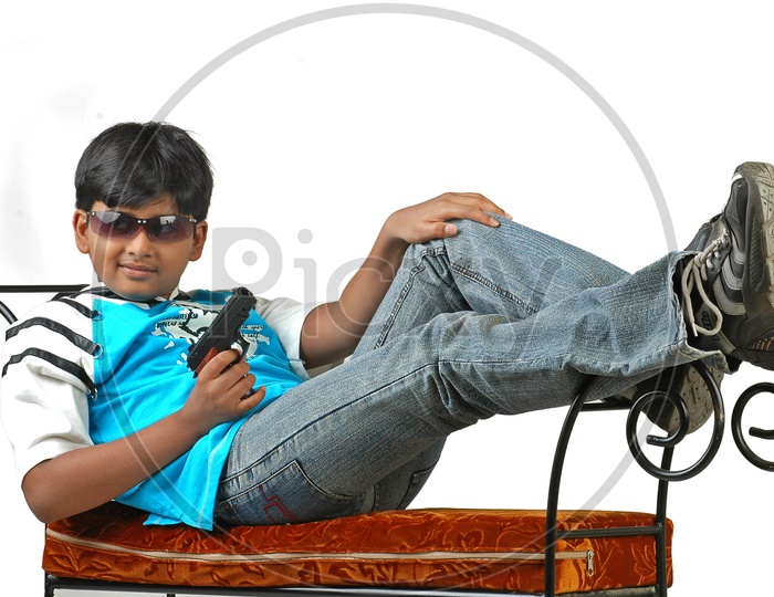 Indian boy wearing sunglasses holding a revolver