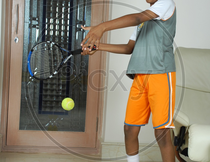 Indian boy playing Tennis in the house
