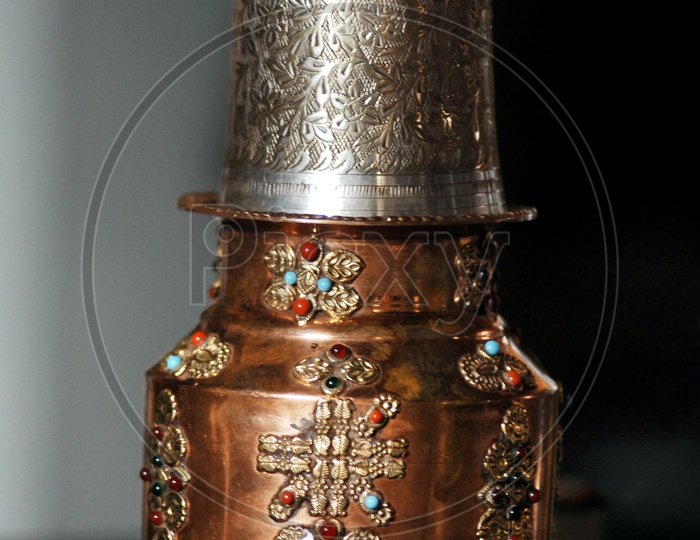 Decorated copper can and a silver glass