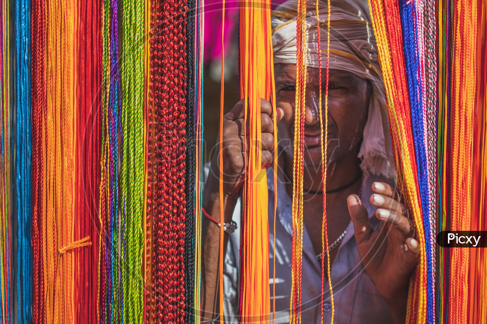 A man on streets selling threads of different colors