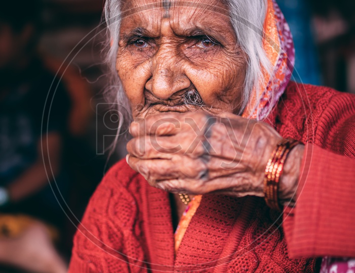 An aged women having a cup of tea in the meantime of selling garlands