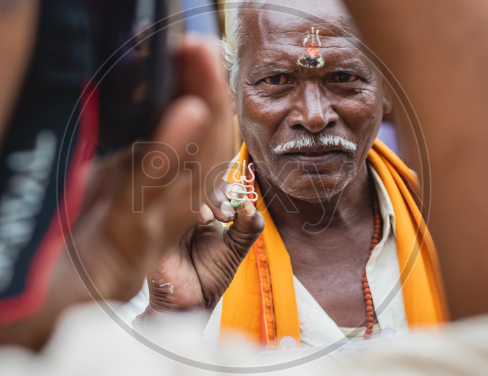 A man trying to make some money by putting a tika on the forehead of people in front on a temple