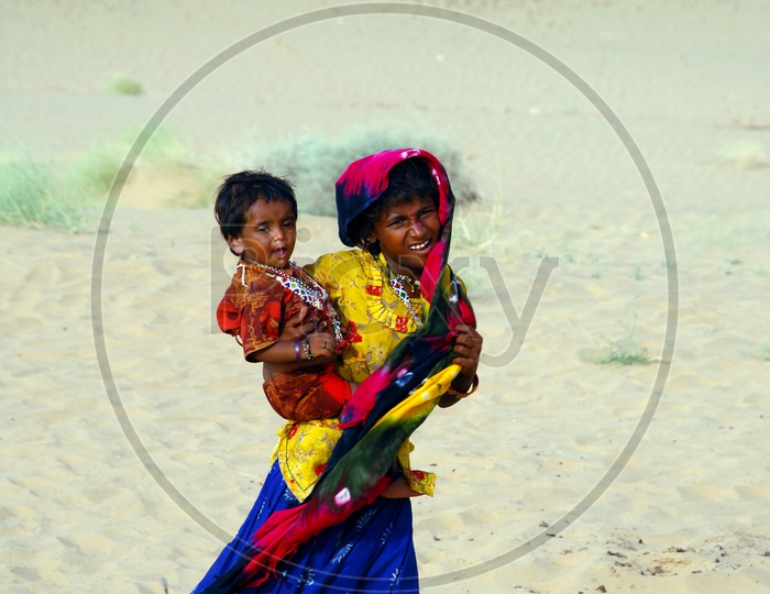 A girl carrying little girl in the desert