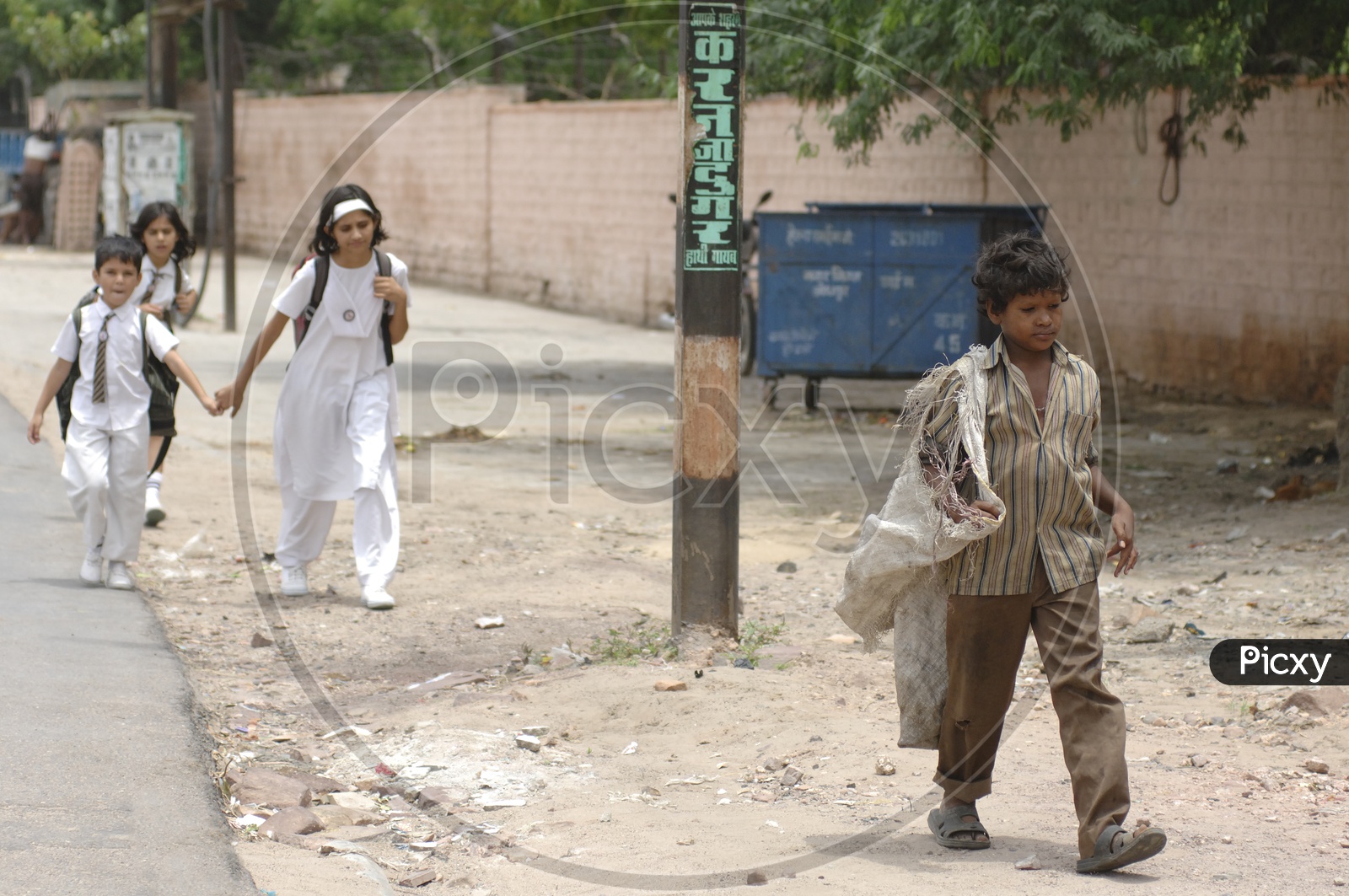 Image of Rag picker boy child in front of the school kidsDQ860155Picxy