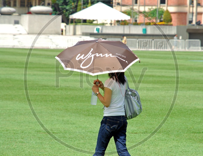 A Young Woman Walking with Umbrella In Hand