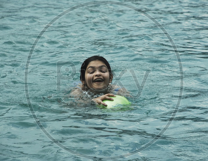 Indian girl playing with a ball in swimming pool