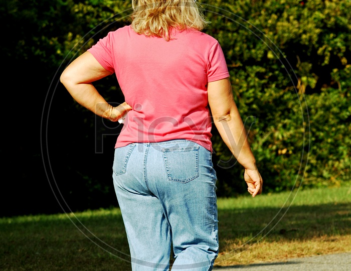 A blonde woman wearing jeans and a pink shirt
