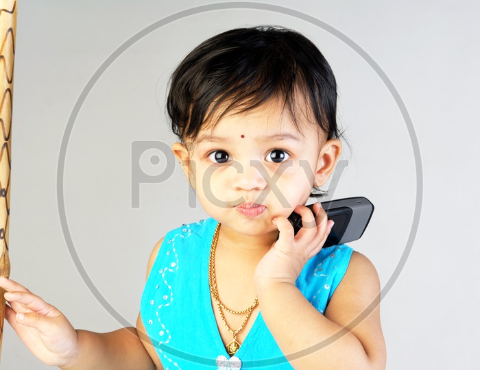 Baby girl in blue frock with a mobile phone